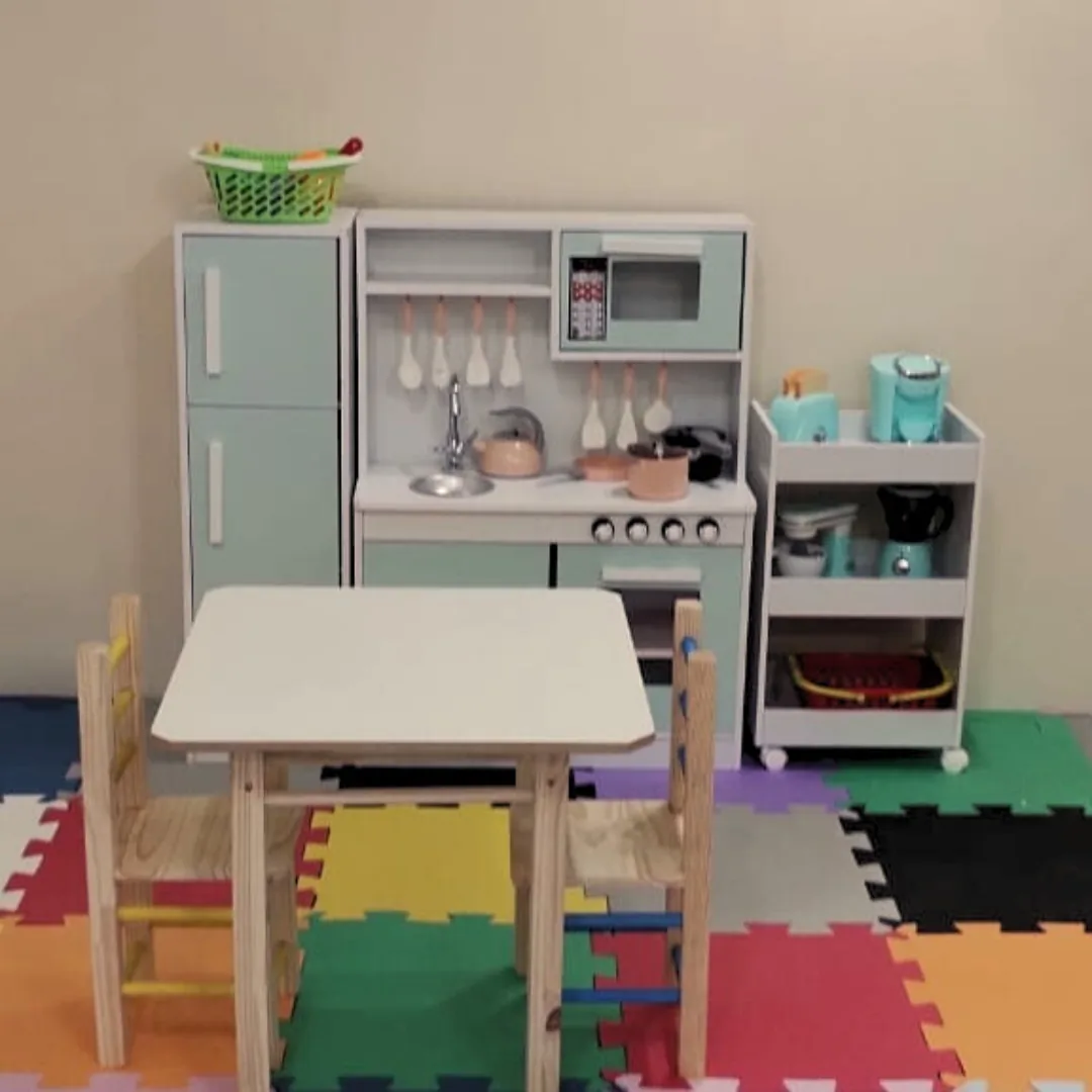 Sala lúdica com cozinha de brinquedo, mesa infantil e tapete emborrachado