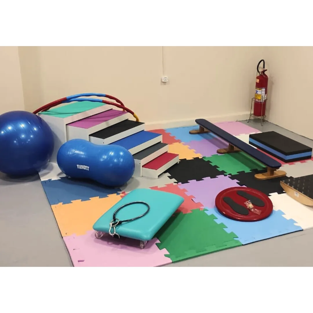 Sala de psicomotricidade com bolas suíças, tatames coloridos e materiais de apoio