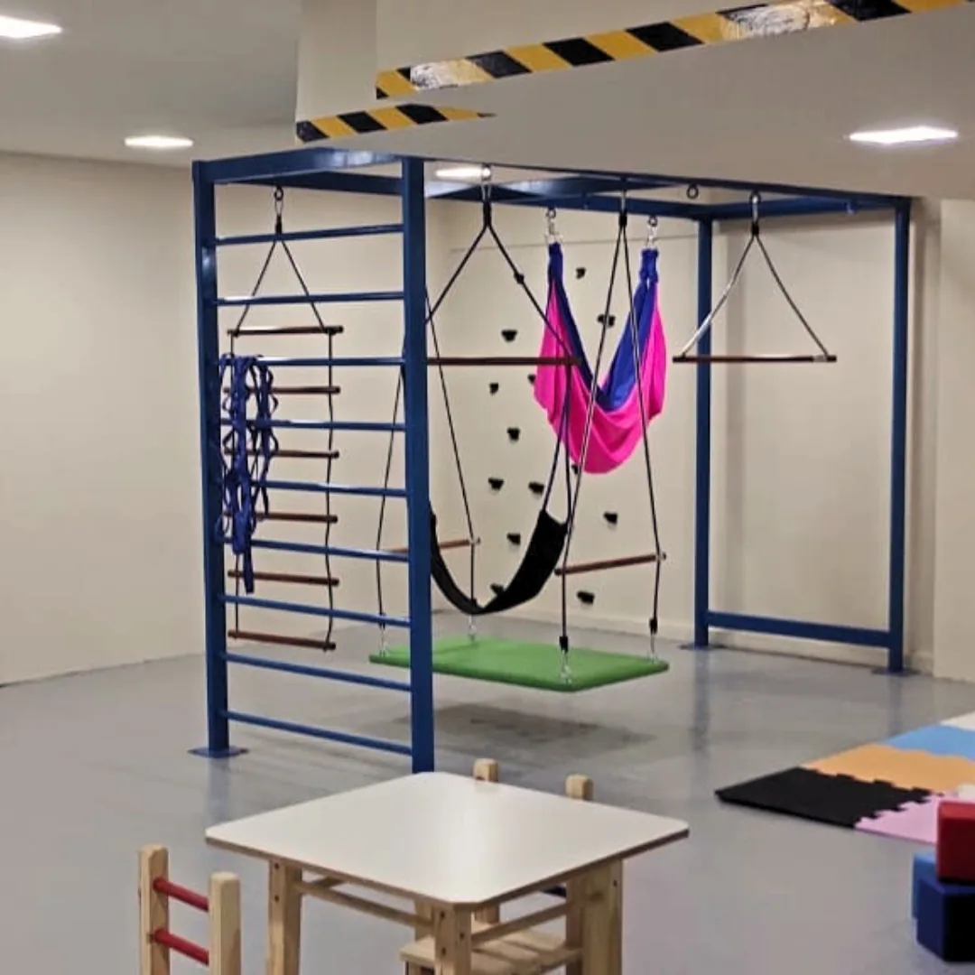 Sala de integração sensorial com parede de escalada, rede e tatames
